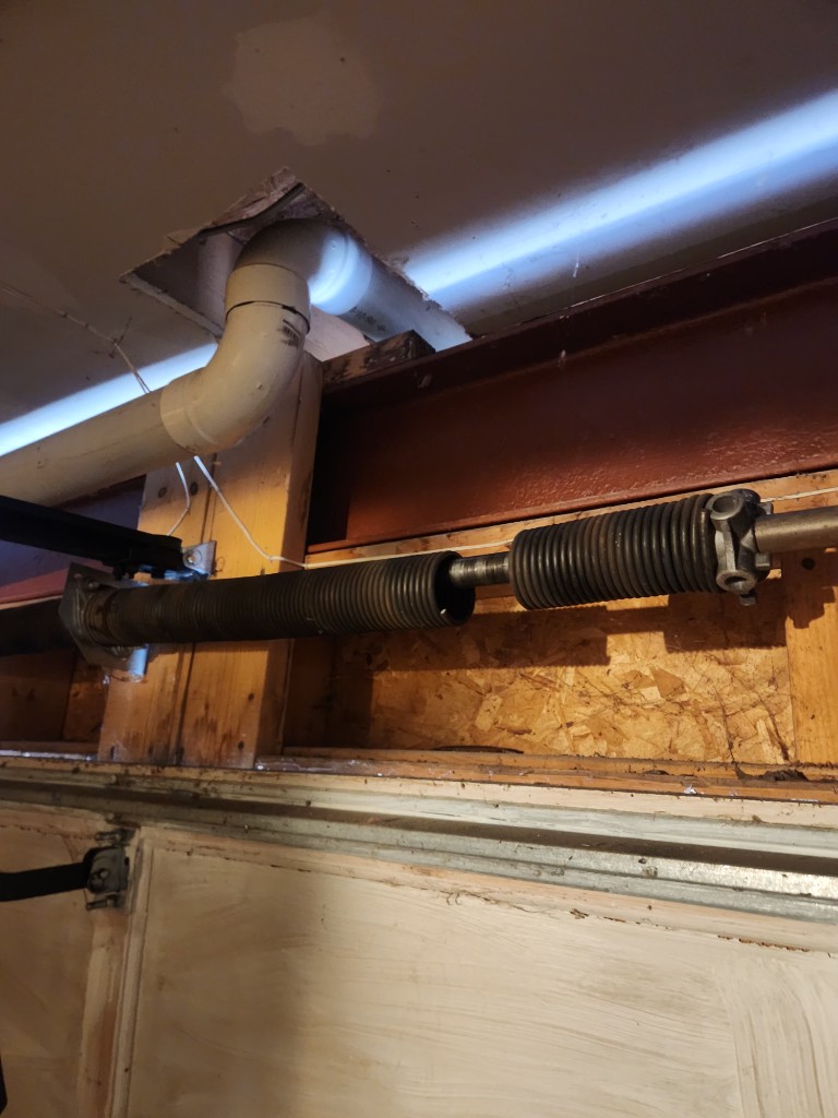 Broken garage door torsion spring snapped in two on the shaft — Ottawa